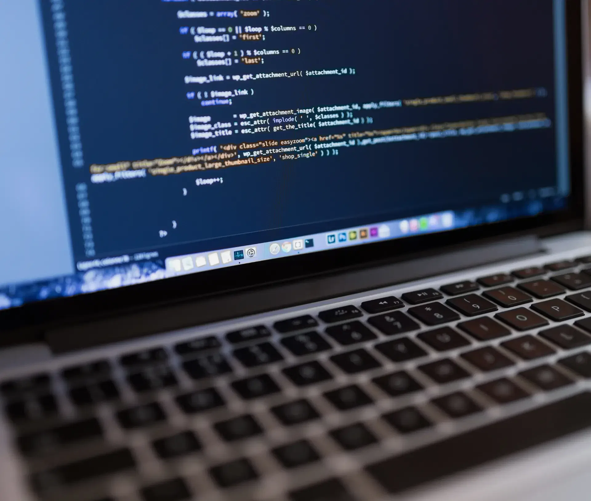Close up of a laptop keyboard with a blurred screen displaying lines of code in a text editor, highlighting software development focused on compliance and data subject access request (DSAR) processing.
