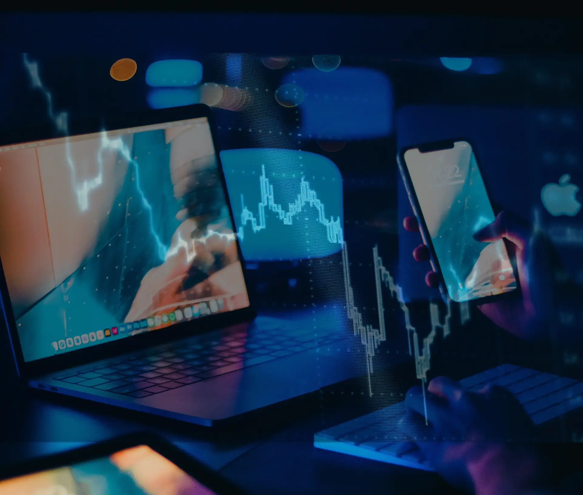 A person uses a laptop and smartphone in a dark room, with glowing financial graphs and stock market charts superimposed on the image, highlighting digital trading and technology—an apt visual for exploring Macs Total Cost of Ownership in finance.