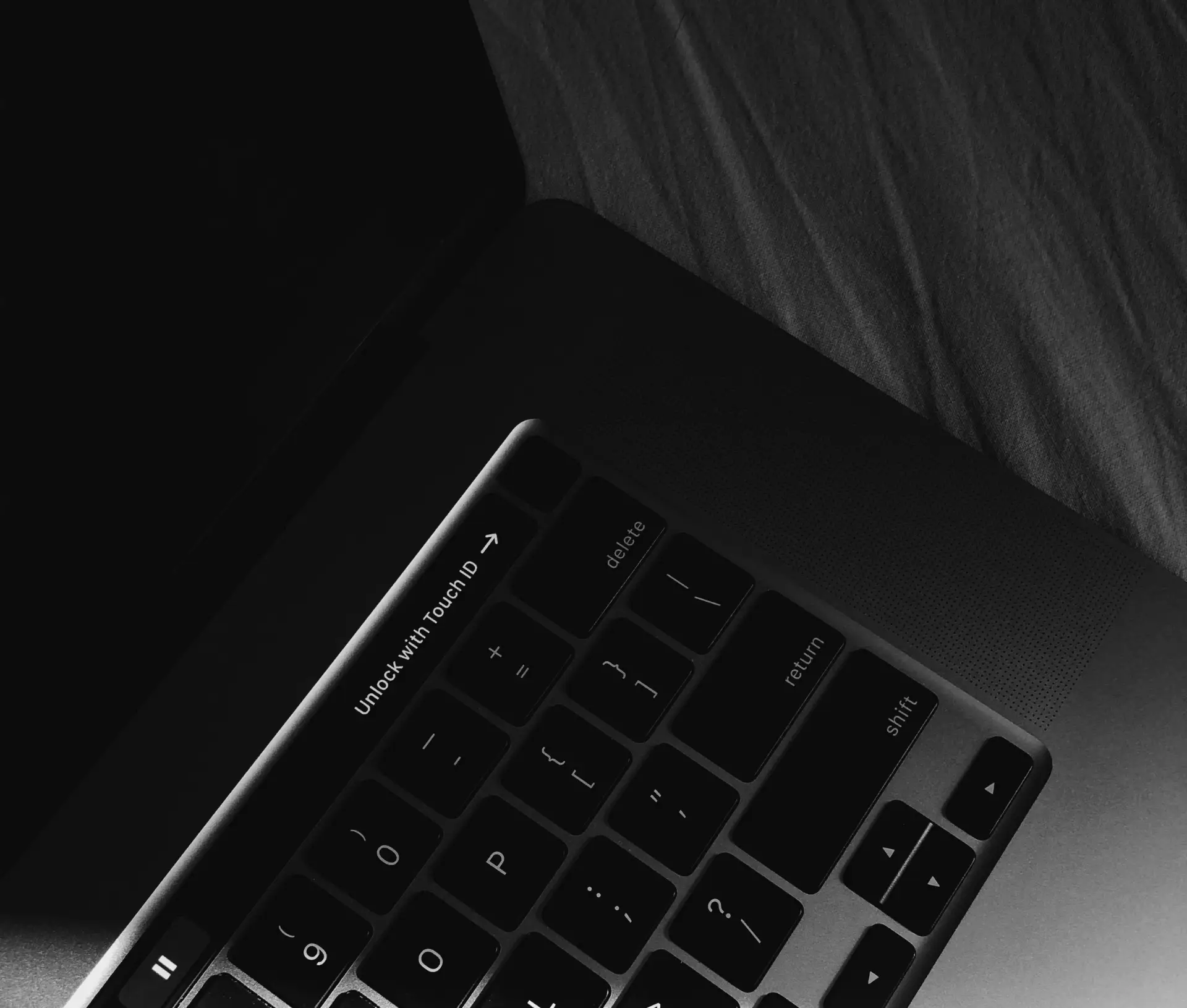 A close up, black and white photo of a laptop keyboard with a visible 
