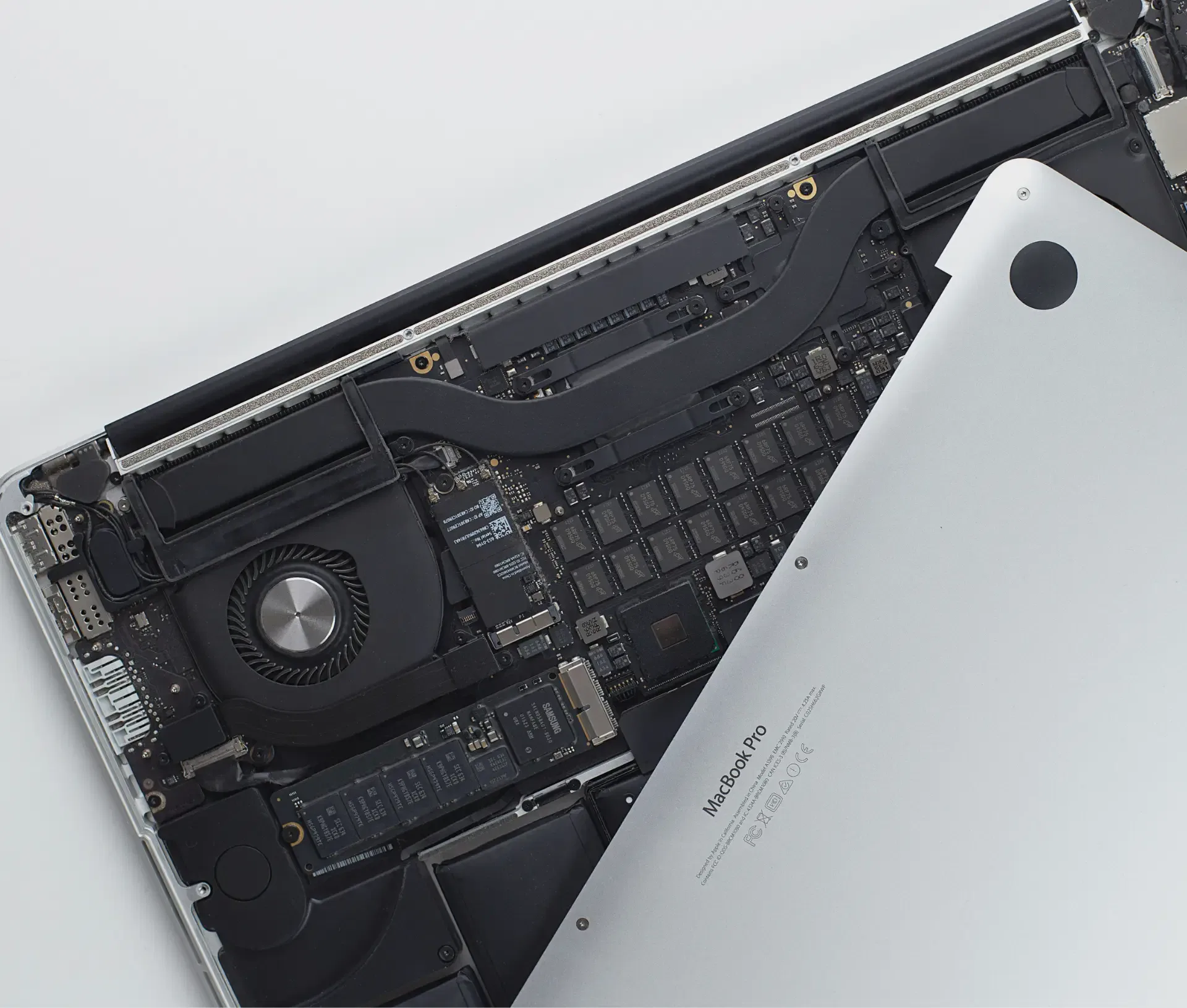 A MacBook Pro with its bottom cover partially removed, revealing internal components like the cooling fan and battery cells—perfect for anyone interested in the circular economy or considering an Apple trade in for business savings.